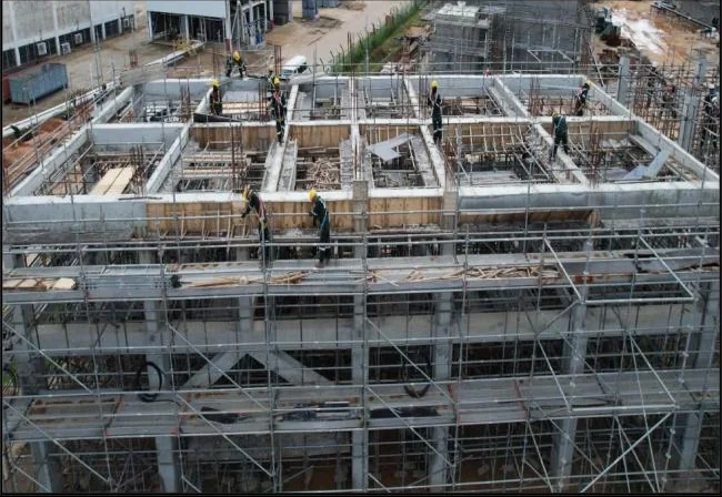 Workers and scaffolding around concrete structures under construction